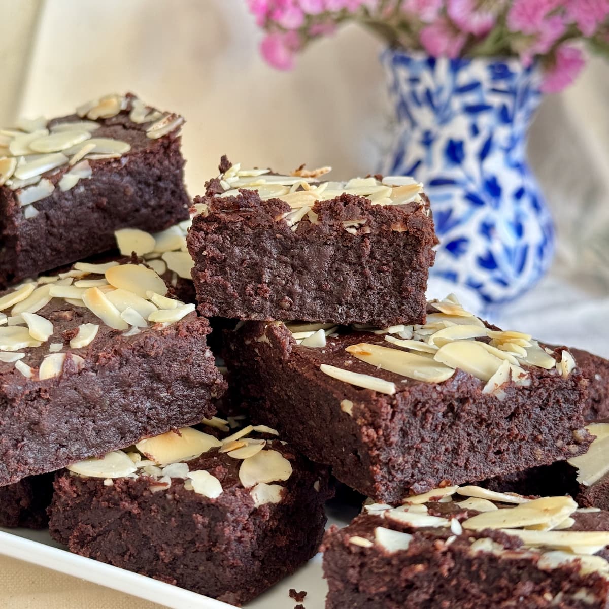 plate of gooey gluten free brownies made with almond flour and melted chocolate, topped with almonds