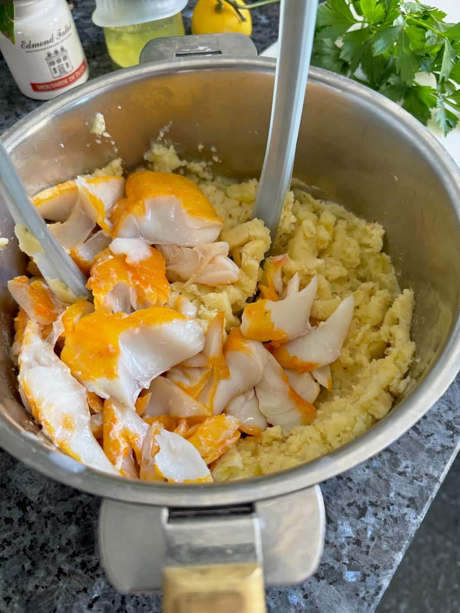 mixing together mashed potato with flaked smoked haddock