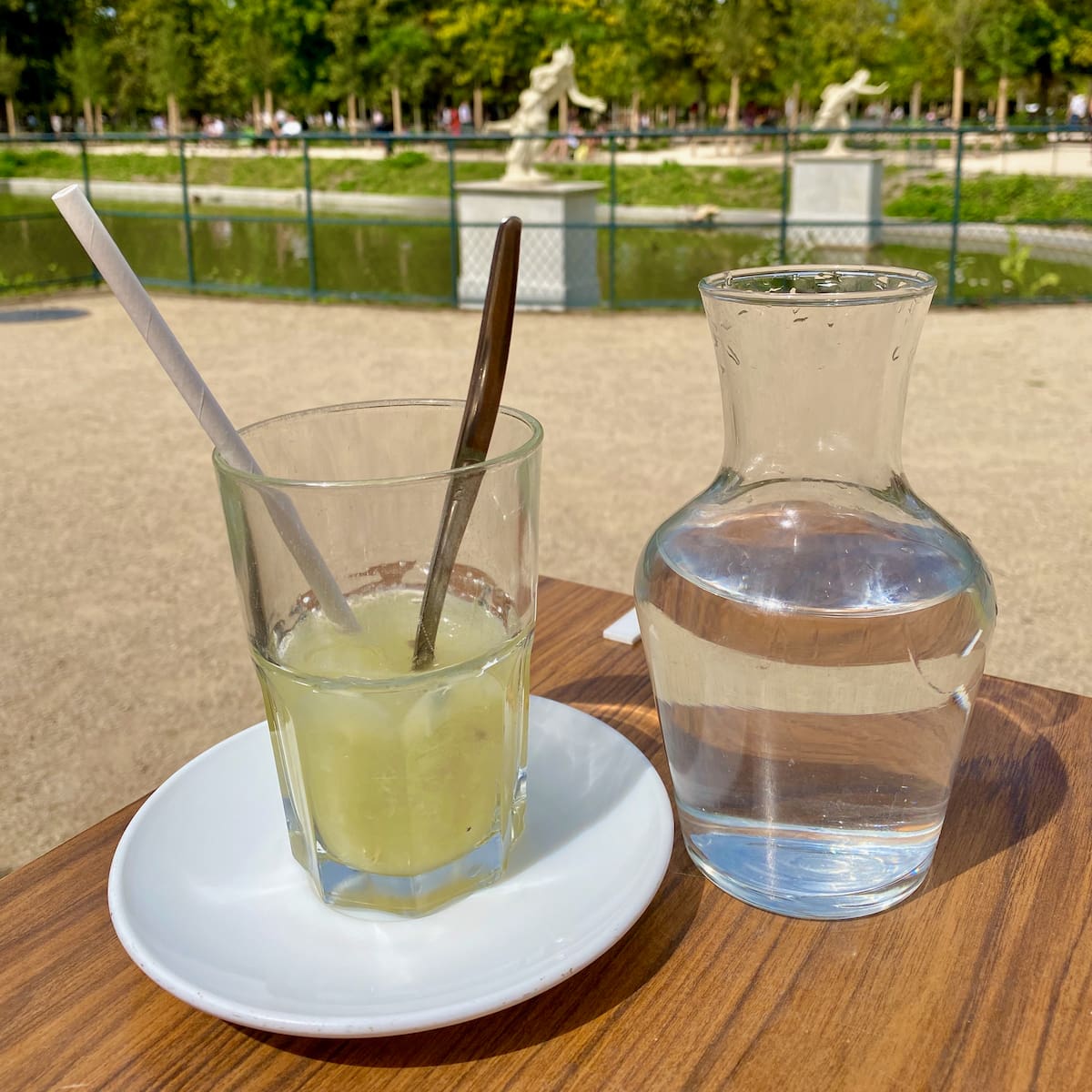 freshly squeezed lemon in a tall tumbler glass with a carafe of water, known as Citron Pressé in Paris' Tuileries gardens